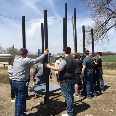 High school, junior high and many other community members working to place the foundation poles.
