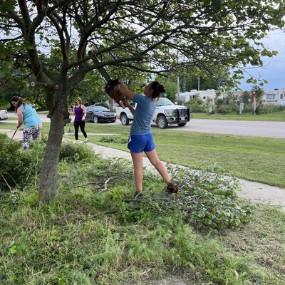 Willing Workers 4-H Club cleaning up trees and other debris around the front steps of the church